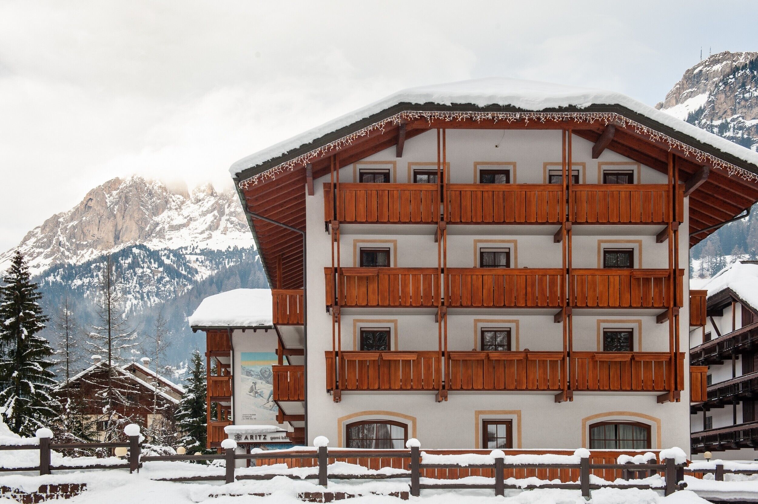 A multi-story building with wooden balconies, surrounded by snow-covered mountains.