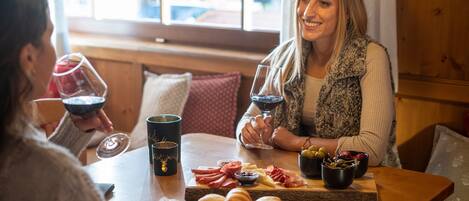 A wooden table with a charcuterie board, wine glasses, and a cup.