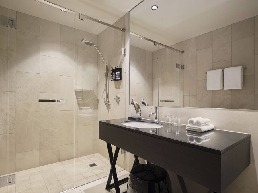 A modern bathroom with a glass-enclosed shower, a dark vanity with a sink, and a large mirror.