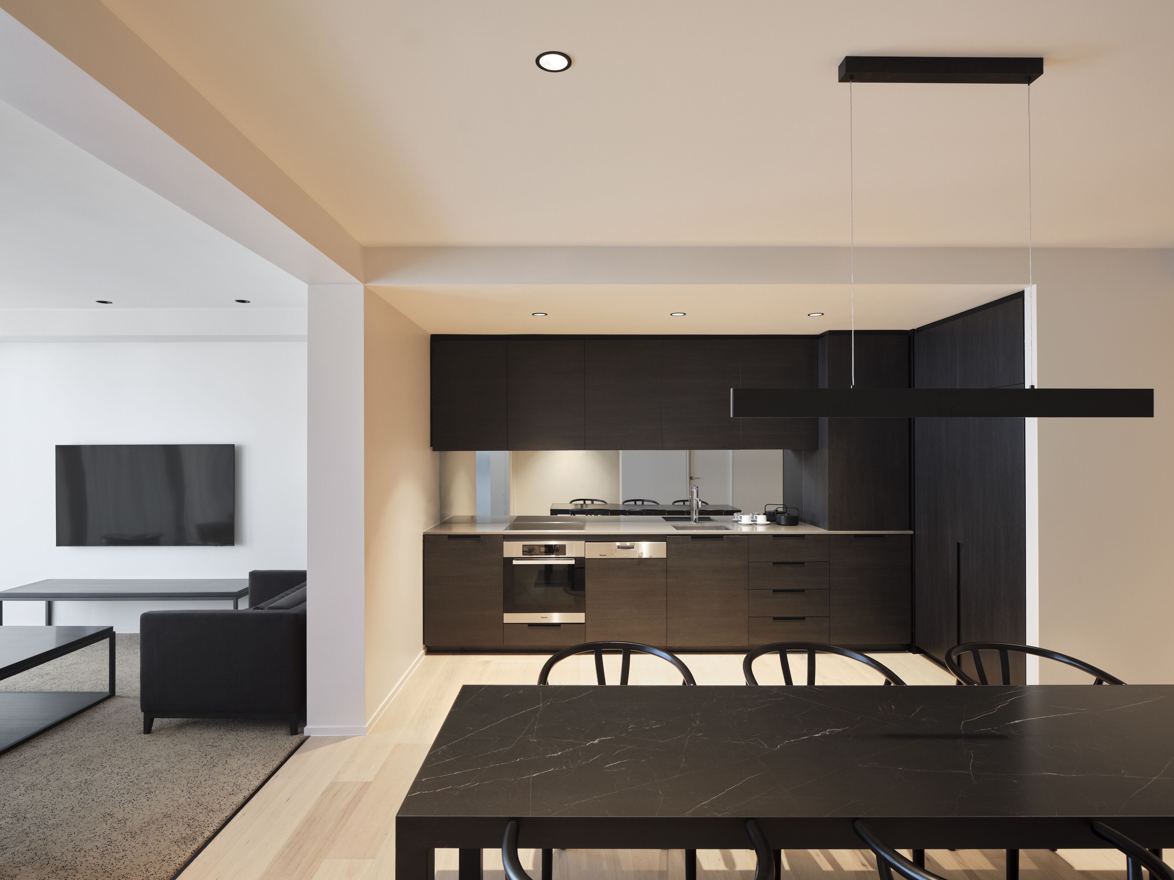 Una cocina moderna con armarios oscuros, una mesa de comedor negra y un diseño minimalista.