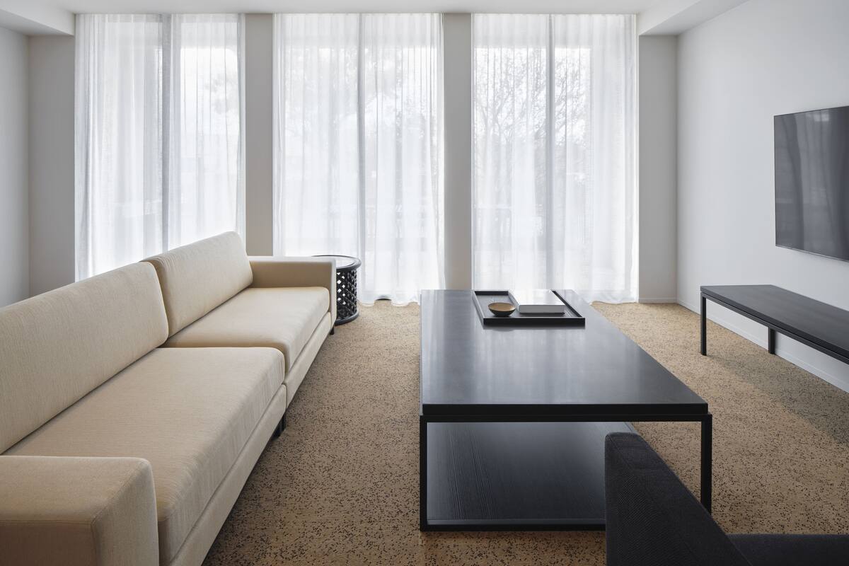 A modern living room with a sofa, a coffee table, and a TV mounted on the wall.