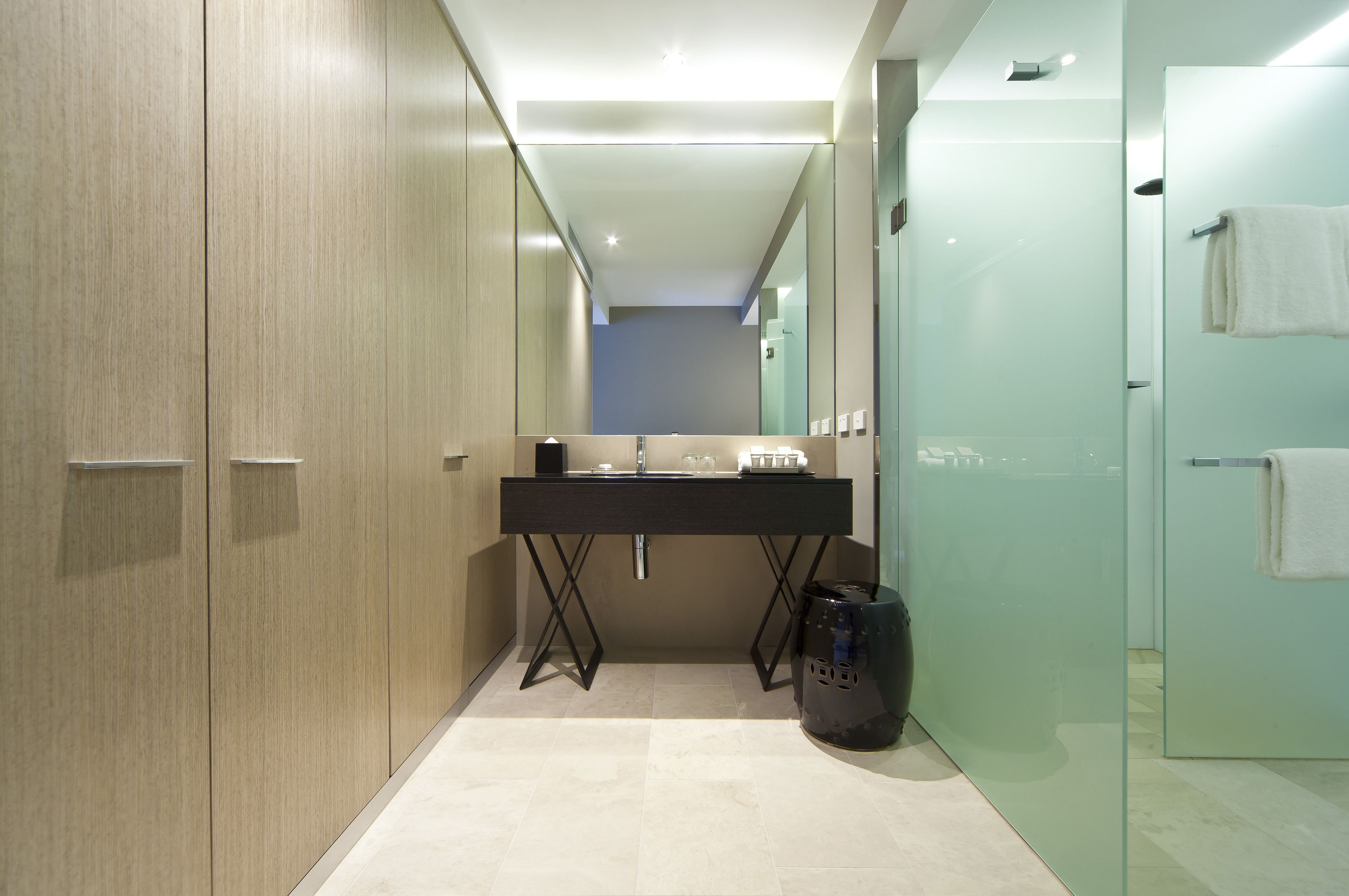 A modern bathroom with a large mirror, a black sink, and a glass shower enclosure.