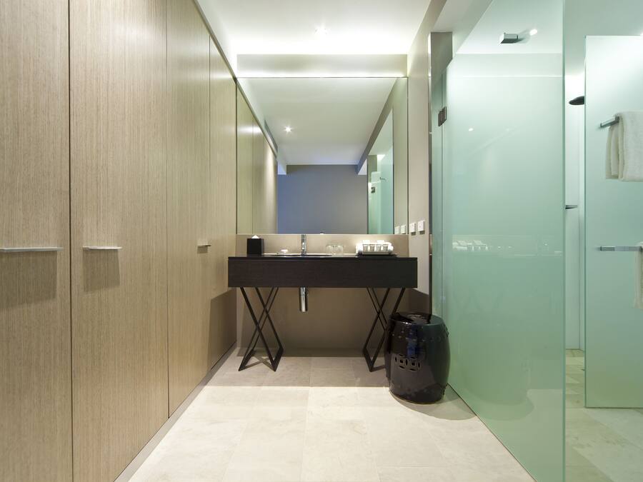 A modern bathroom with a large mirror, a black sink, and a glass shower enclosure.