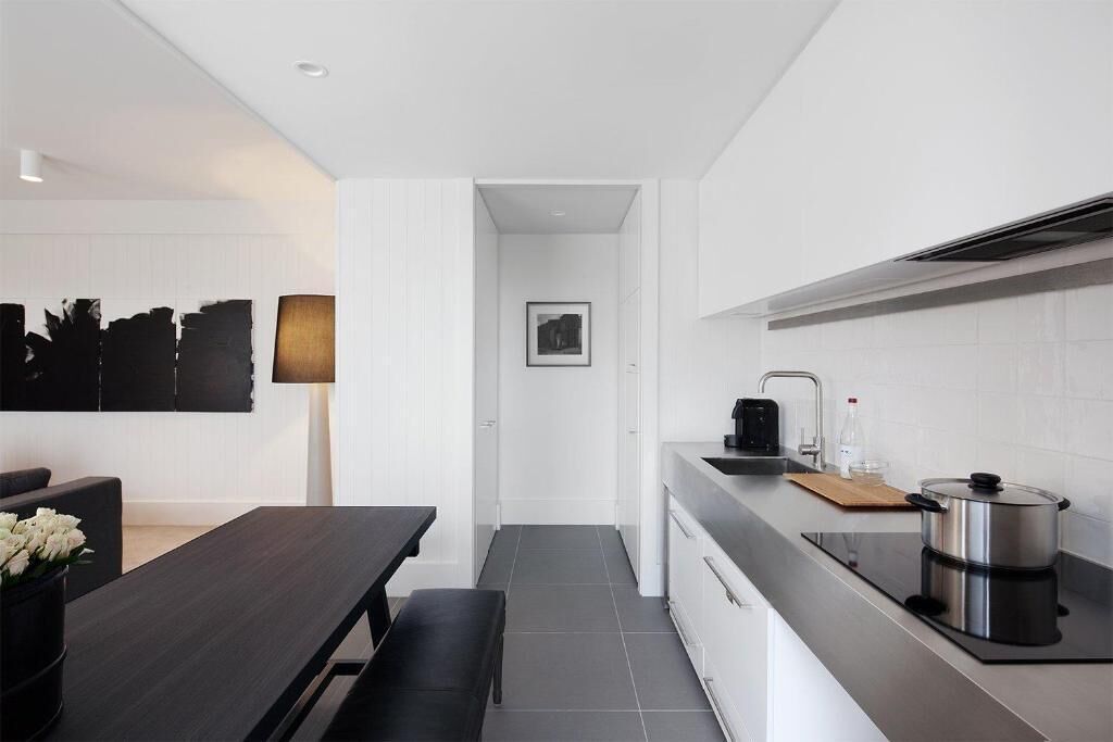 A modern kitchen with a dark countertop, white cabinets, and a black stove.