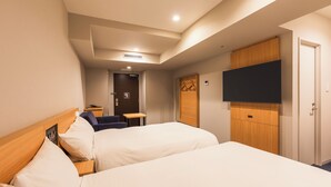 Habitación de hotel con dos camas, televisión, escritorio y armario.