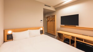 Une chambre d’hôtel comprenant un lit, une table de chevet, une télévision et un bureau avec une chaise.