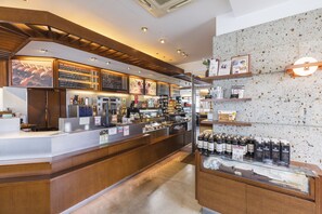 L’intérieur d’un café, avec un comptoir, des panneaux affichant le menu et des étagères remplies de boissons.