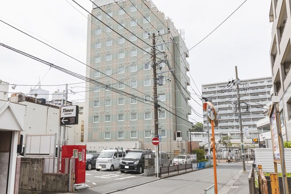 A multi-story building with a Times parking sign, a no entry sign, and a Coca-Cola vending machine.