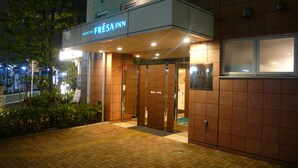 L’entrée d’un hôtel, avec une enseigne indiquant « FRESA INN » et une porte en bois.