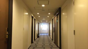Un pasillo de hotel con pisos alfombrados, puertas a ambos lados e iluminación empotrada en el techo.