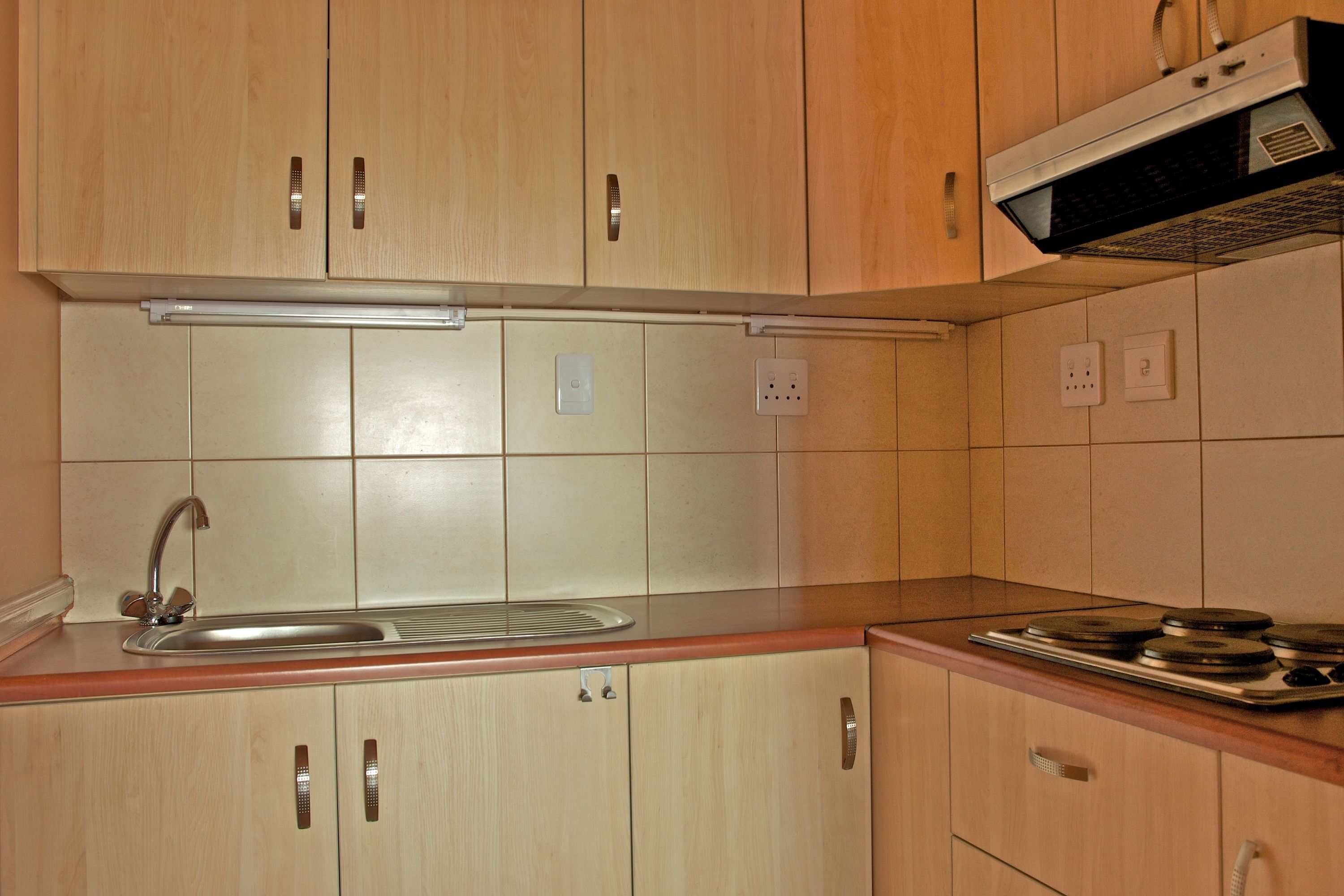 Una cocina con armarios de madera, un lavamanos de acero inoxidable, un microondas y una estufa.