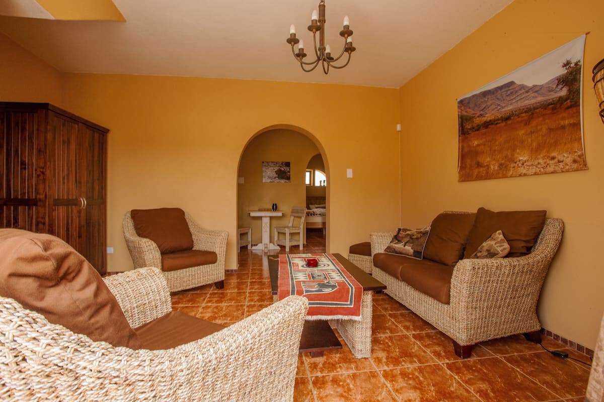 Ein Wohnzimmer mit Rattanmöbeln, einem Couchtisch und einem Gemälde an der Wand.