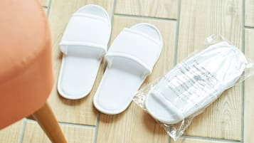 A pair of white slippers and a plastic package with text on a wooden floor.