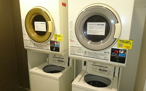 Two front-loading washing machines with control panels and instruction labels.