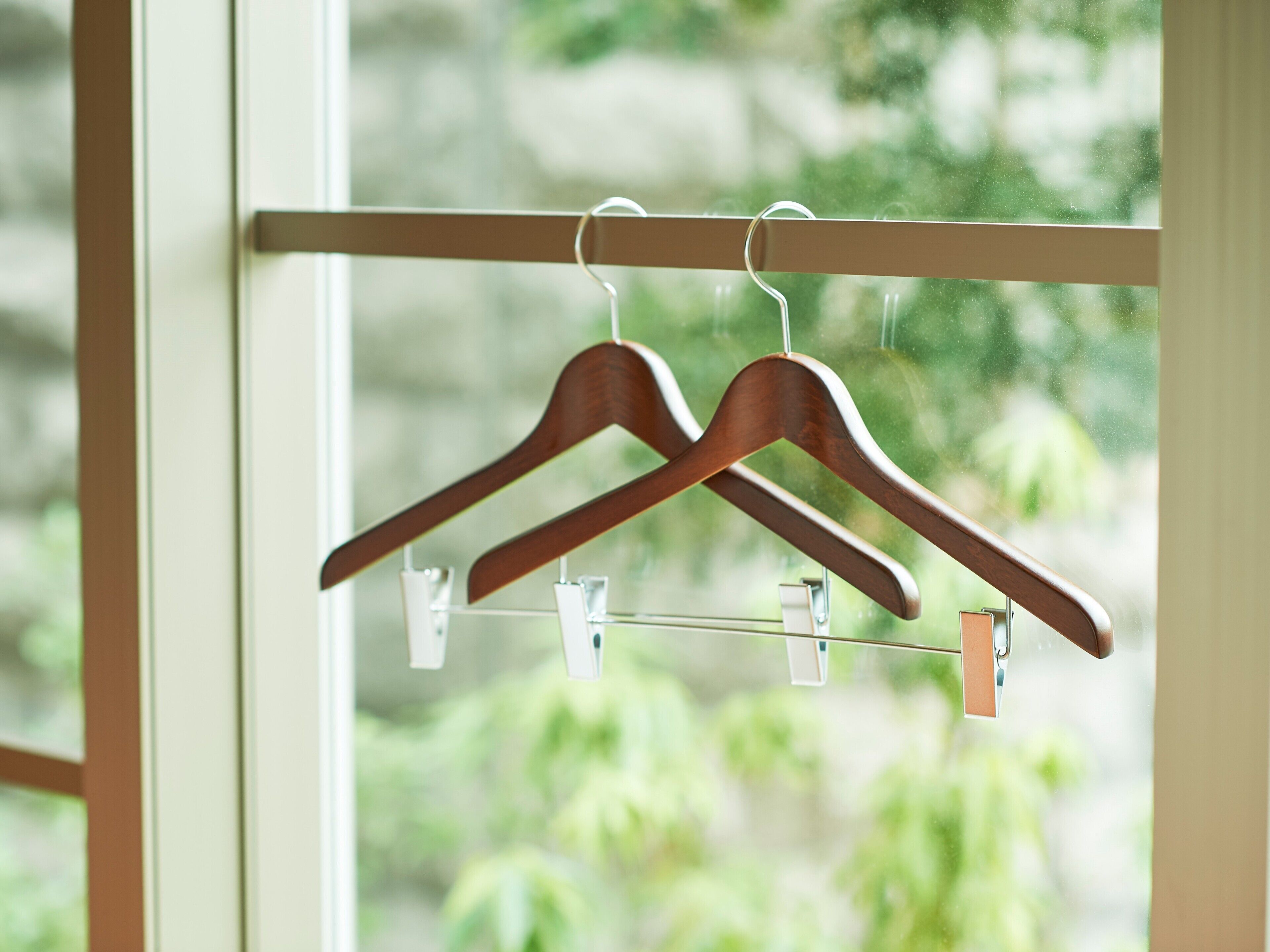 Wooden hangers on a metal rod, likely in a closet or storage area.