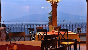 A dining area with a table set for four, overlooking a body of water and mountains. - Hotel Porton Del Cielo (Patzcuaro)