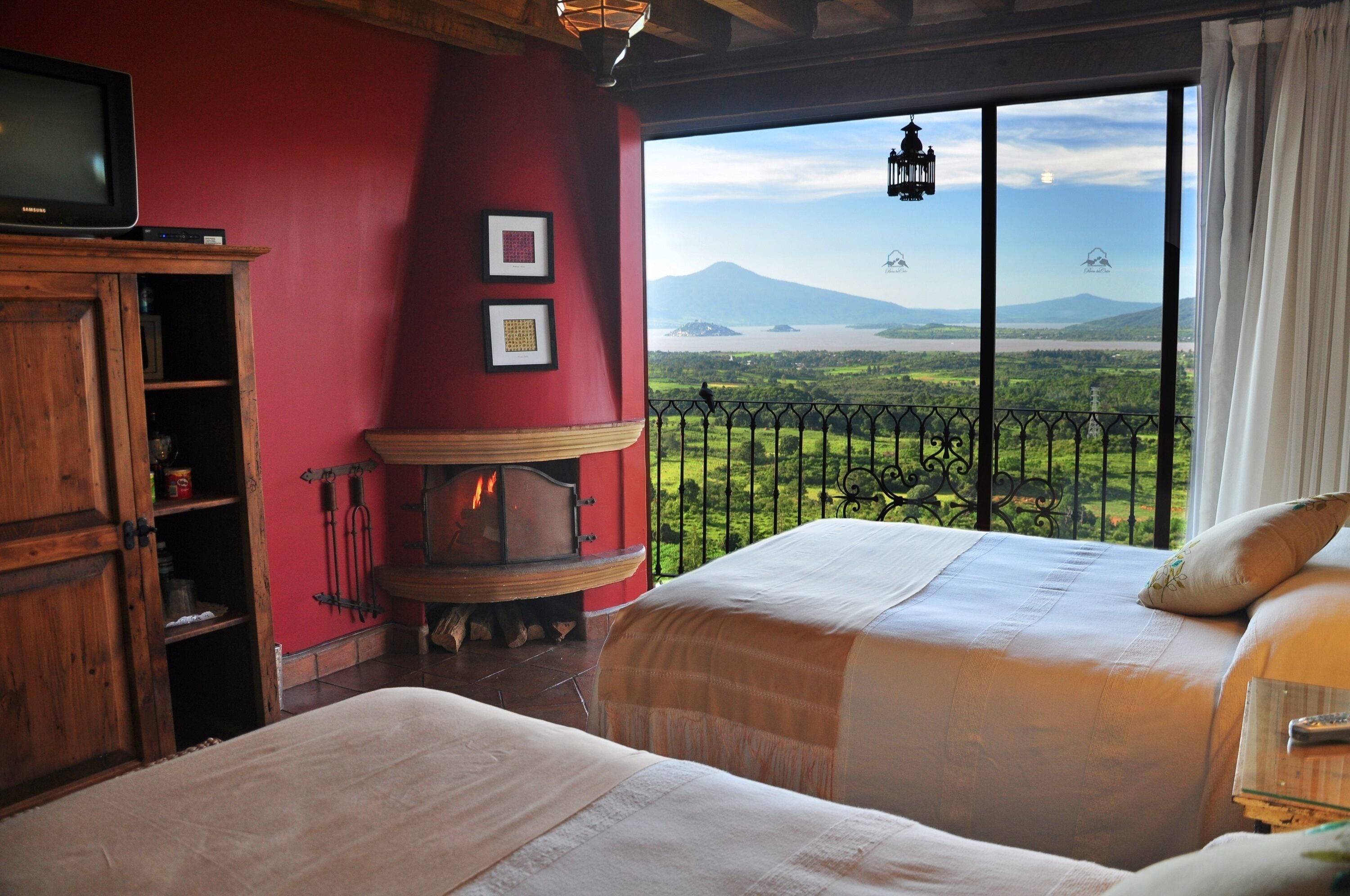 Un dormitorio con dos camas, una chimenea, un televisor y vistas a un paisaje montañoso.
