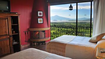 Un dormitorio con dos camas, una chimenea, un televisor y vistas a un paisaje montañoso.