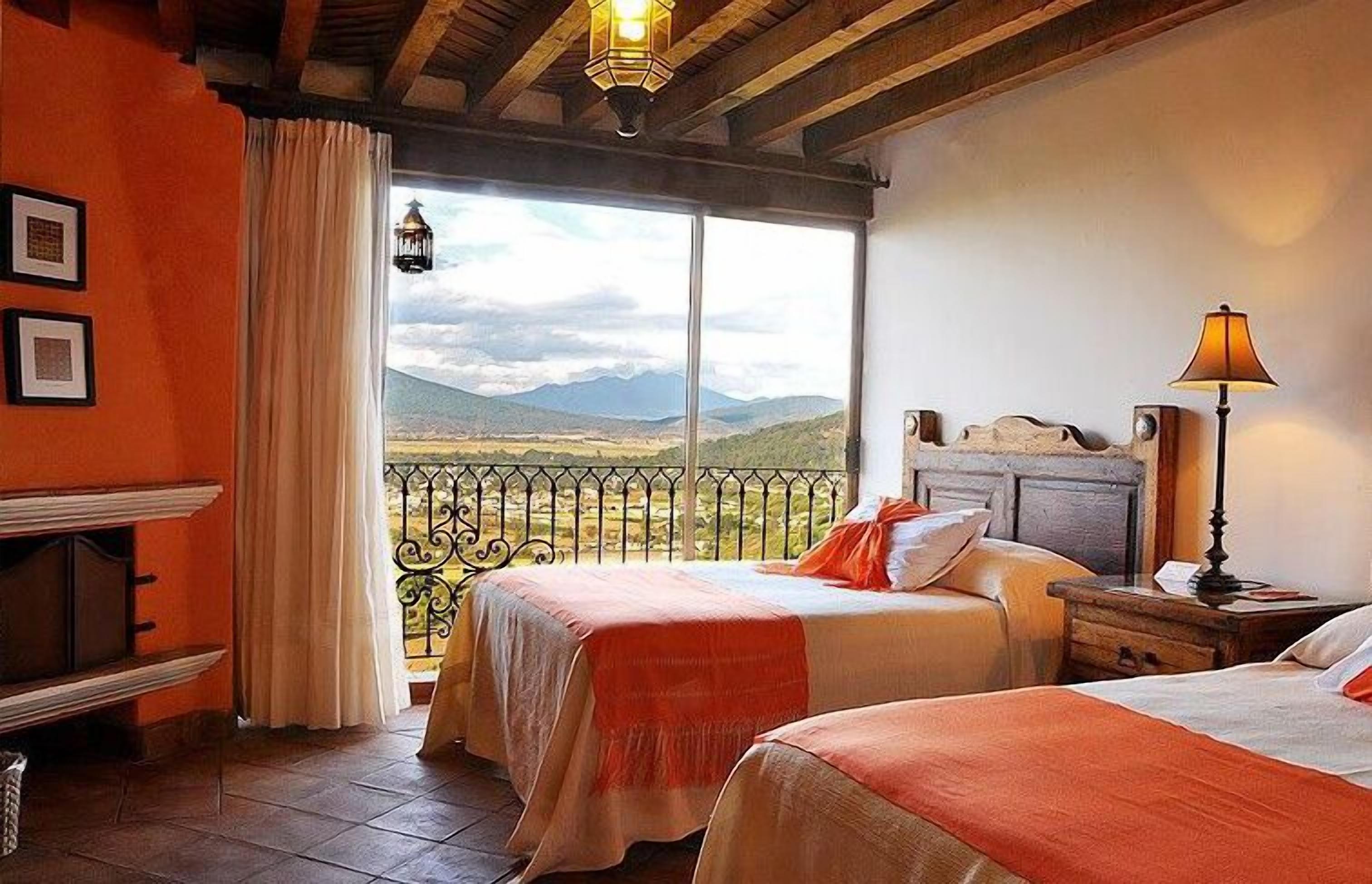 Una habitación con dos camas, un balcón y vistas a las montañas, y techo de madera.
