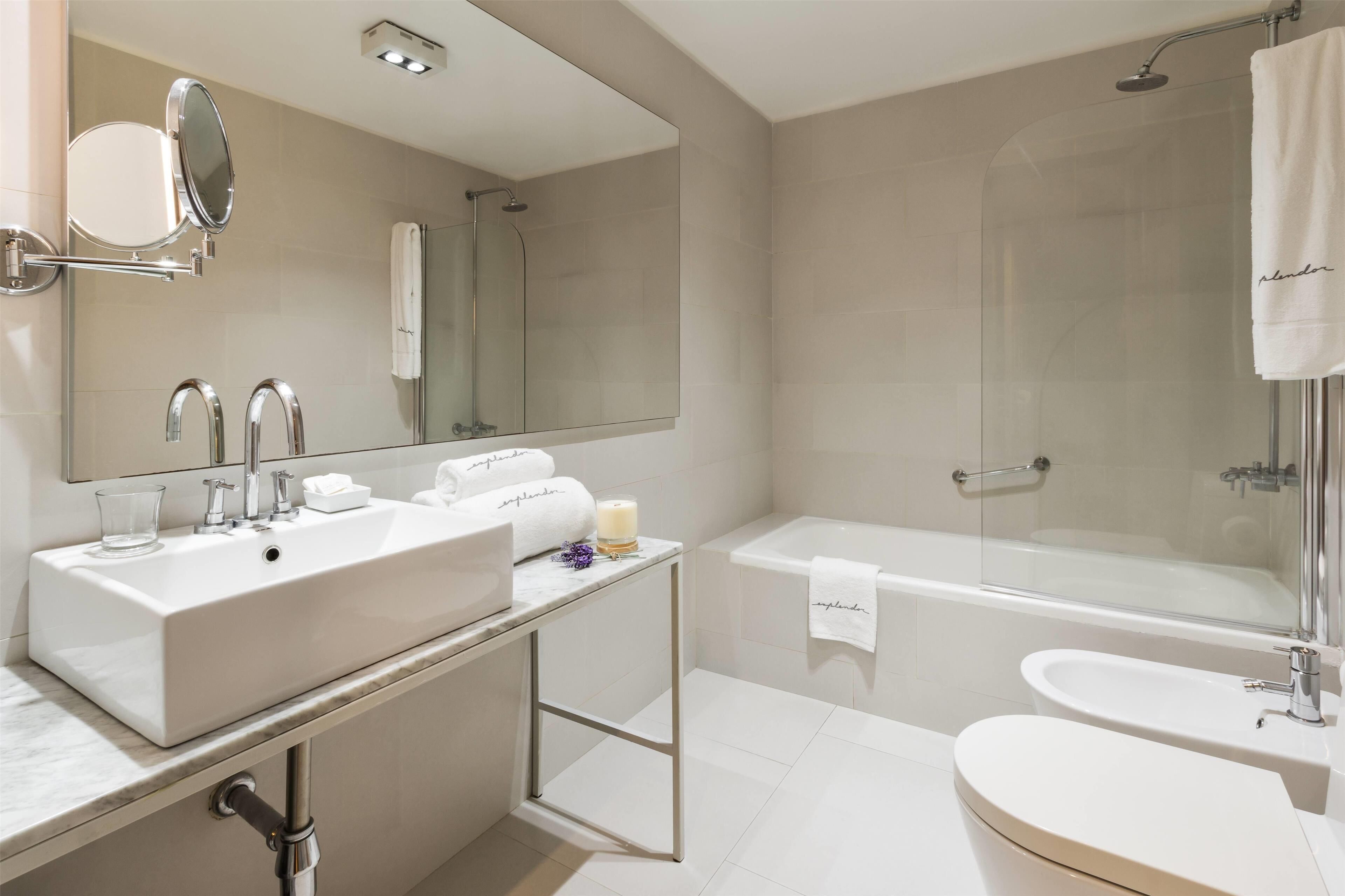 Un baño moderno con lavamanos doble, bañera y ducha con mampara de vidrio.