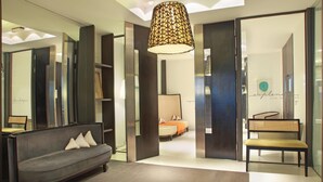 A modern hotel lobby with a sofa, a bench, and a large hanging lamp. - Esplendor by Wyndham Montevideo Cervantes (Montevideo)