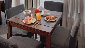 A dining area with a table set for breakfast, a vase with flowers, and a cityscape view. - Esplendor by Wyndham Montevideo Cervantes (Montevideo)