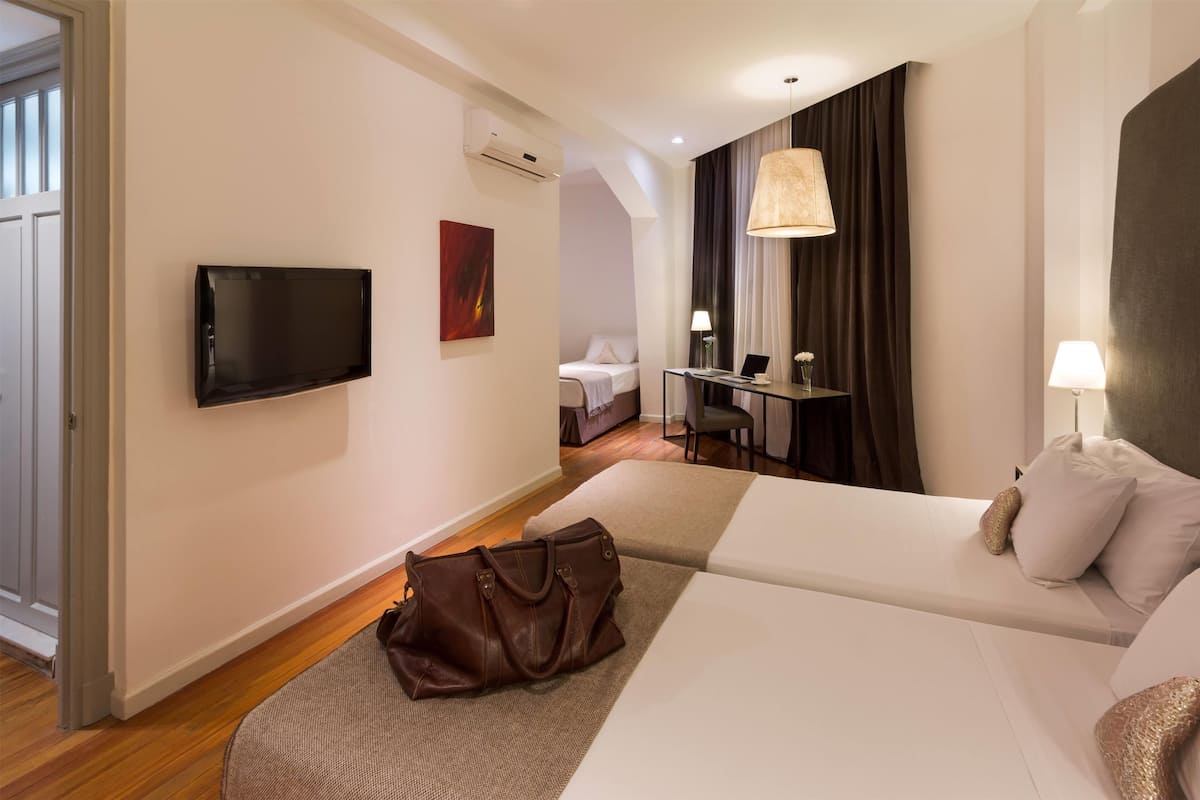 Hotelkamer met een bed, een bureau, een stoel, een televisie en een handtas op de vloer.