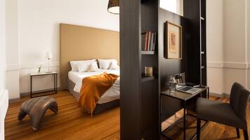 Quarto de hotel moderno com cama, mesa de cabeceira, abajur e escrivaninha com cadeira.