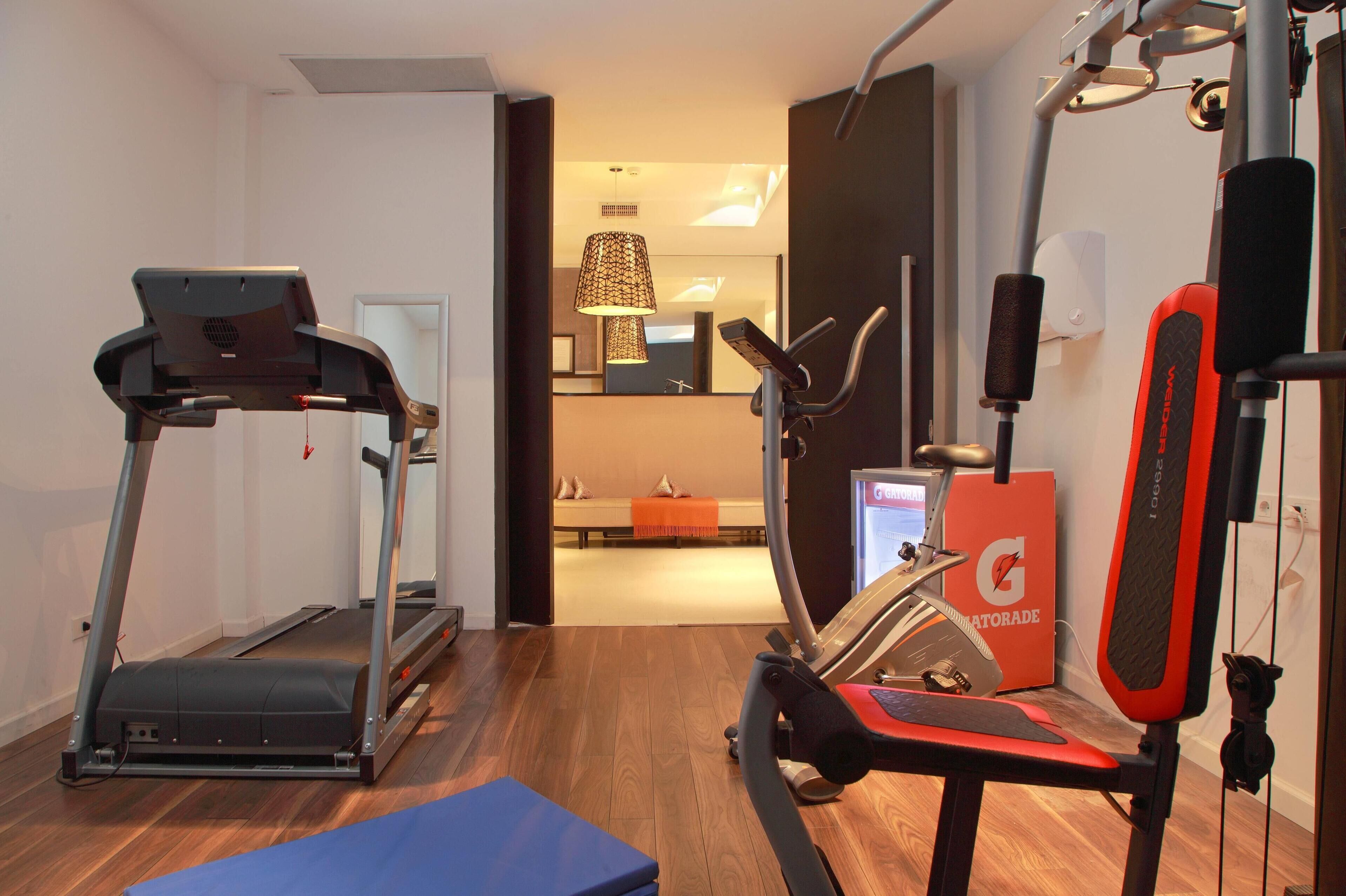 Un gimnasio en casa con cinta de correr, bicicleta estática y banco de pesas.