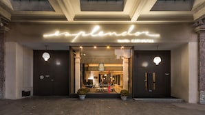 The entrance of the Explendor Hotel with a modern design, featuring a neon sign, large glass doors, and a well-lit interior visible through the doors. - Esplendor by Wyndham Montevideo Cervantes (Montevideo)