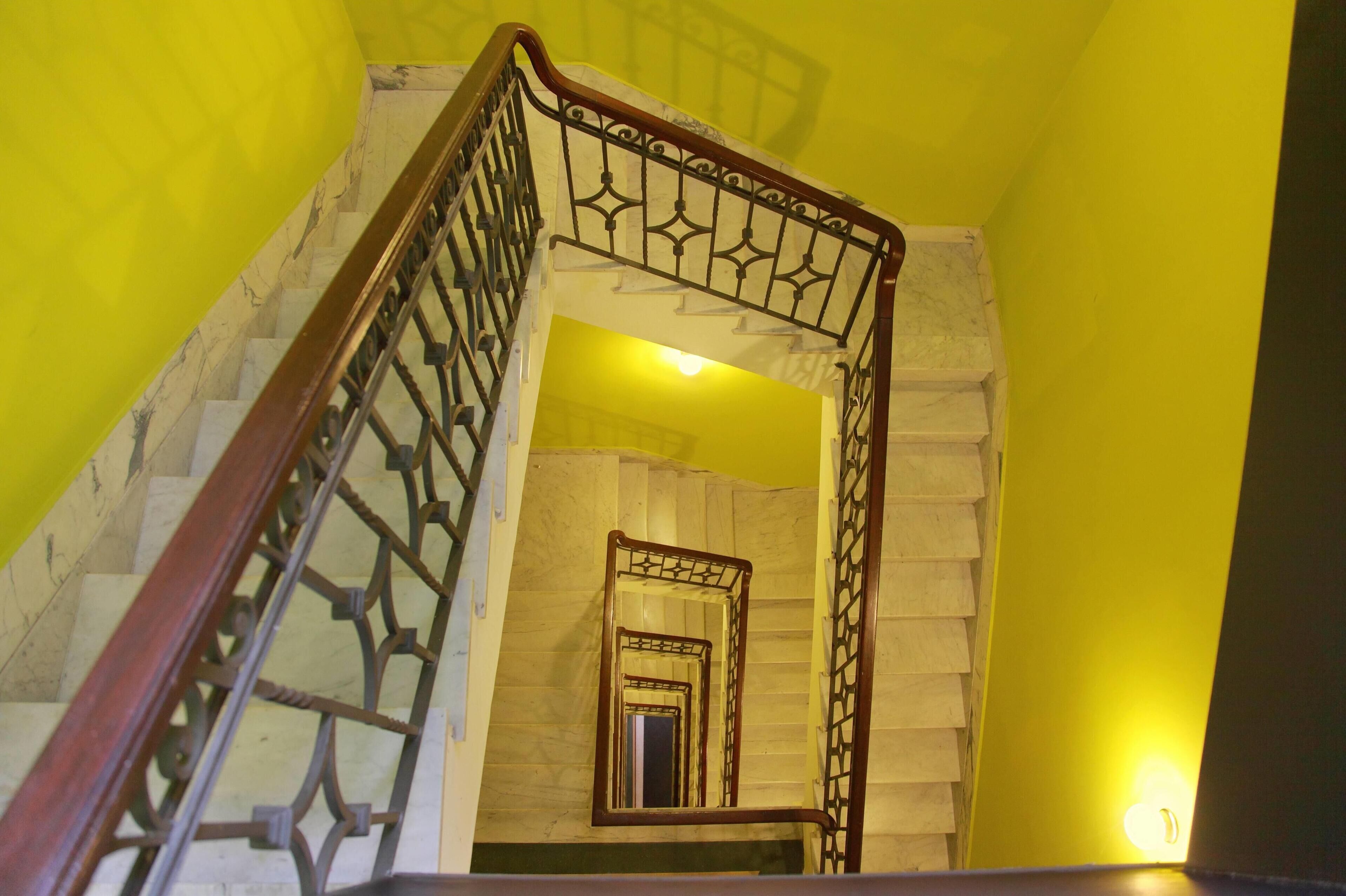 A staircase with a wooden handrail and metal balusters, leading to a landing with a light fixture.