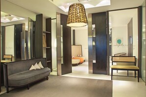 Een moderne hotellobby met een bank, een zitje en een grote hanglamp.