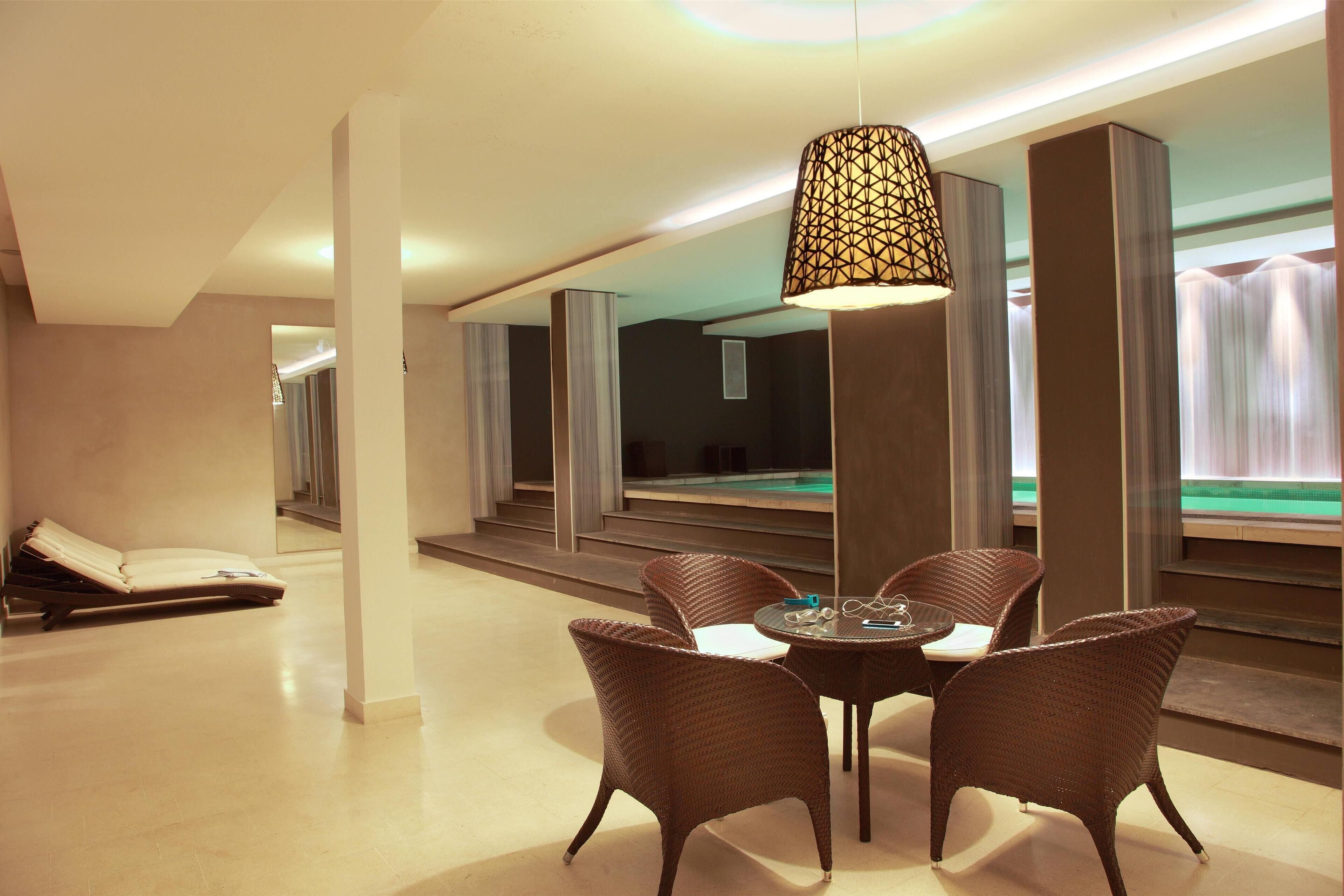 A modern hotel lobby with a lounge area, a pool view, and a dining setup.