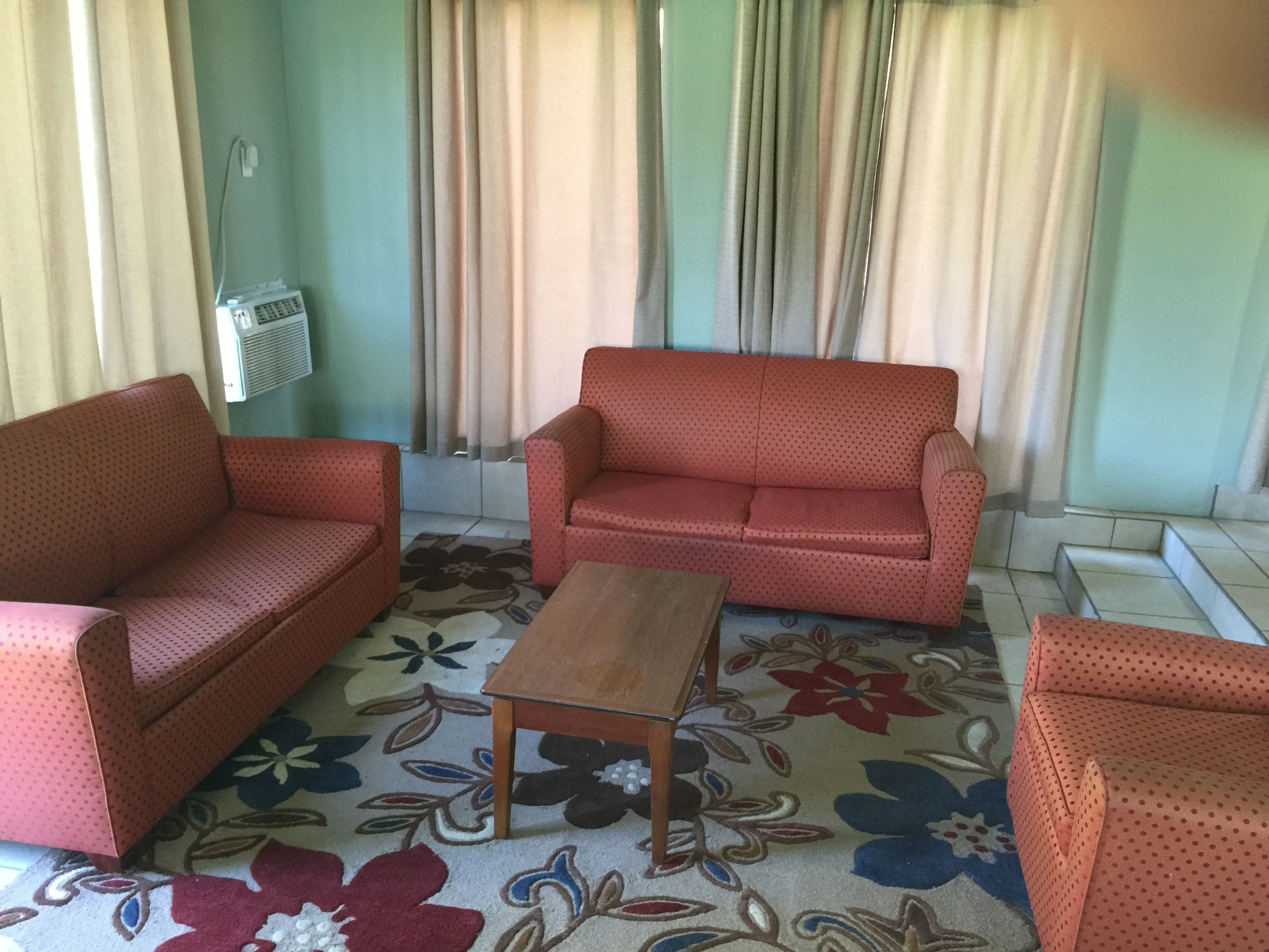 A living room with two red sofas, a wooden coffee table, and a patterned carpet.