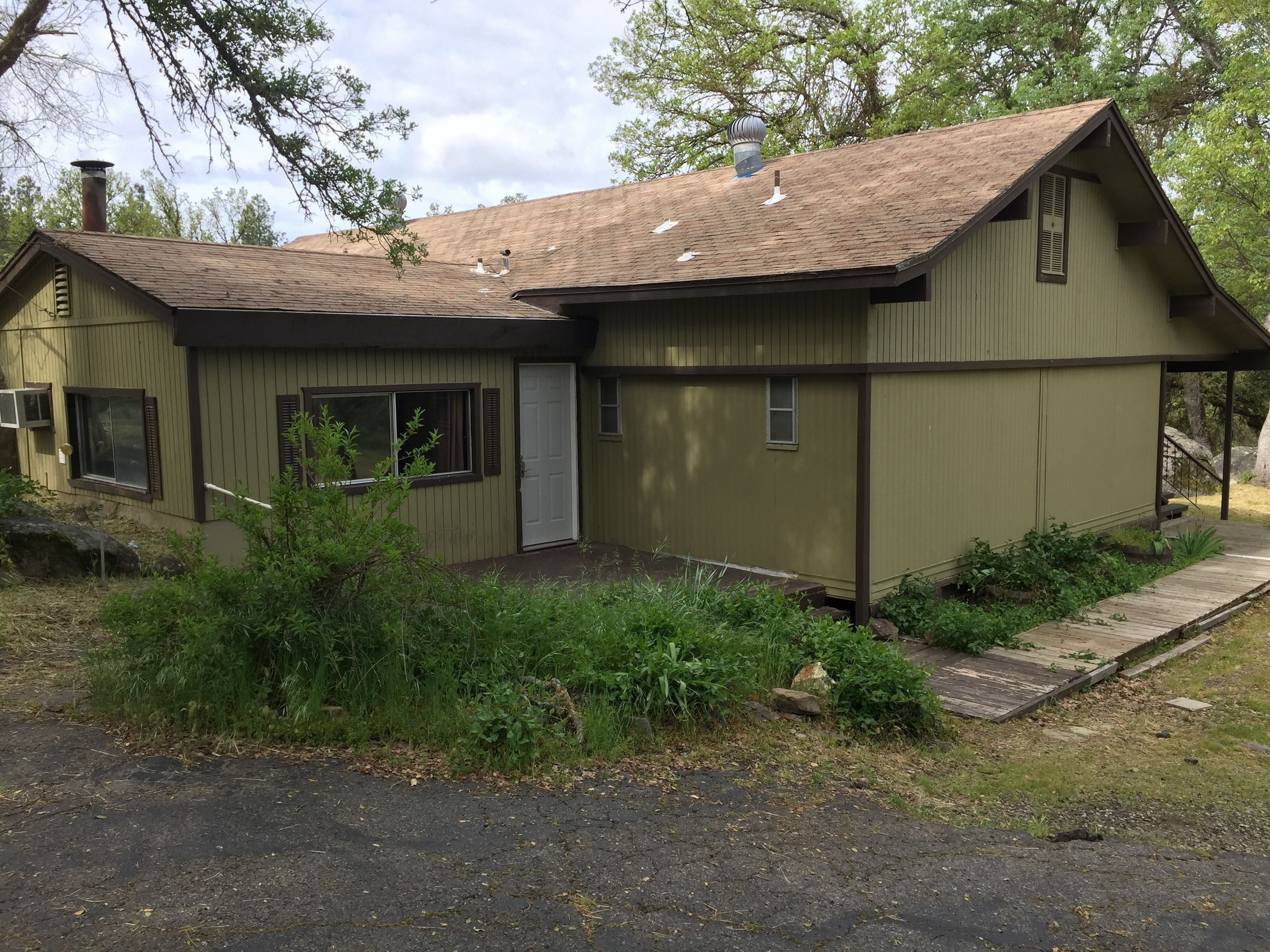 A small, single-story building with a sloped roof, a chimney, and a front porch.