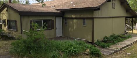 A small, single-story building with a sloped roof, a chimney, and a front porch.