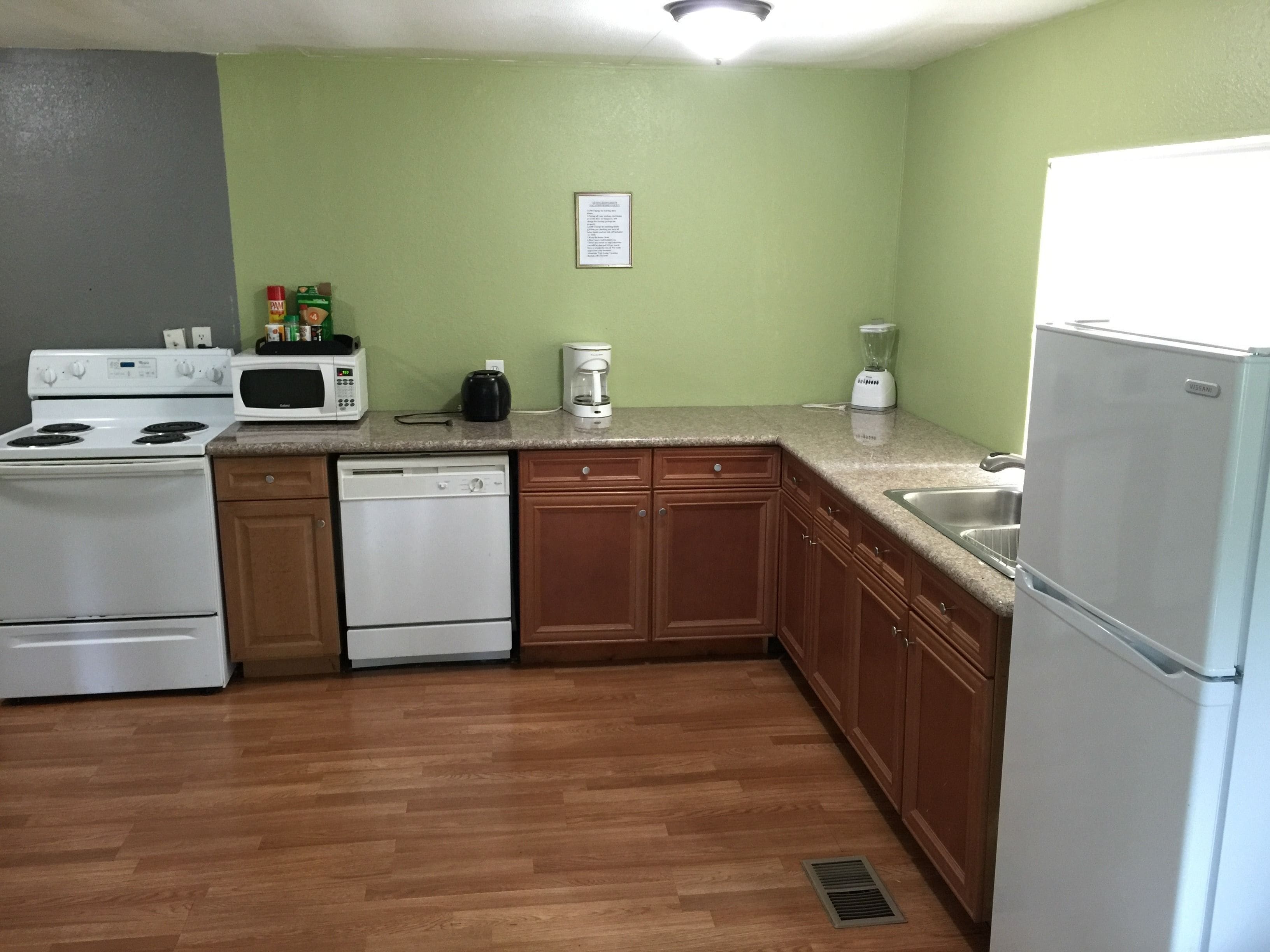 Una cocina equipada con estufa, microondas, cafetera y refrigerador.