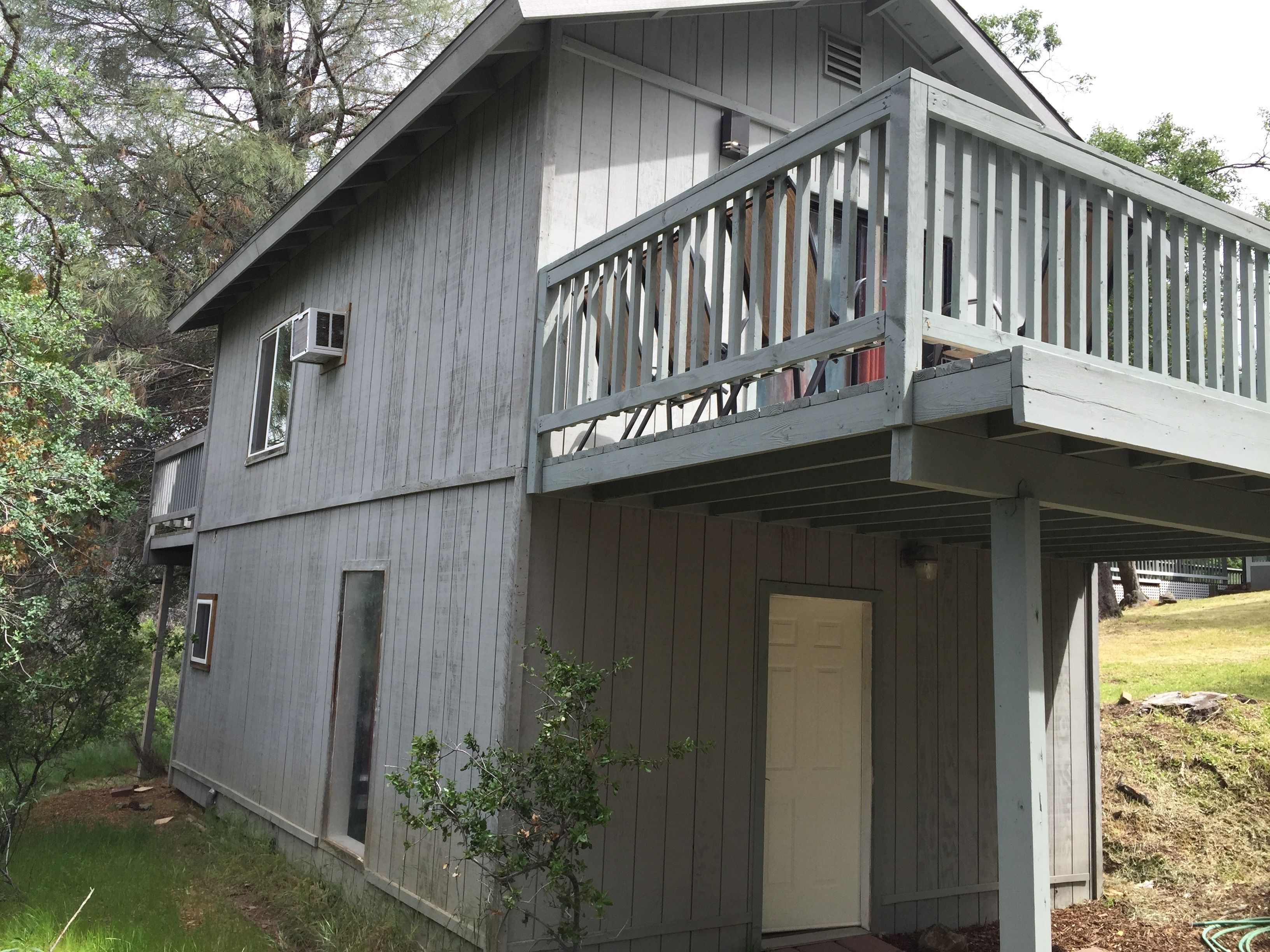 A two-story wooden house with a balcony, a door, and a window.