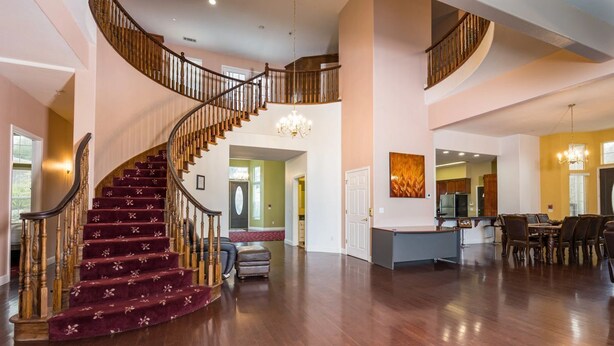 A spacious interior with a grand staircase, a kitchen area, and a dining space. - Mountain Trail Lodge & Vacation Rentals (Oakhurst)