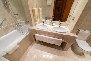 A bathroom with two sinks, a bathtub, and a toilet.