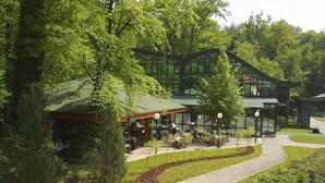 A modern building with a glass facade, surrounded by lush greenery and a paved walkway. - Hotel AS (Zagreb)