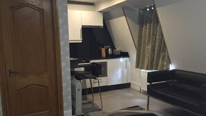 A compact living space with a kitchenette, a dining area, and a seating area. - Paddington Apartments (London)