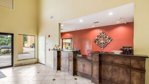 A reception area with a wooden counter, a red accent wall, and a tiled floor.