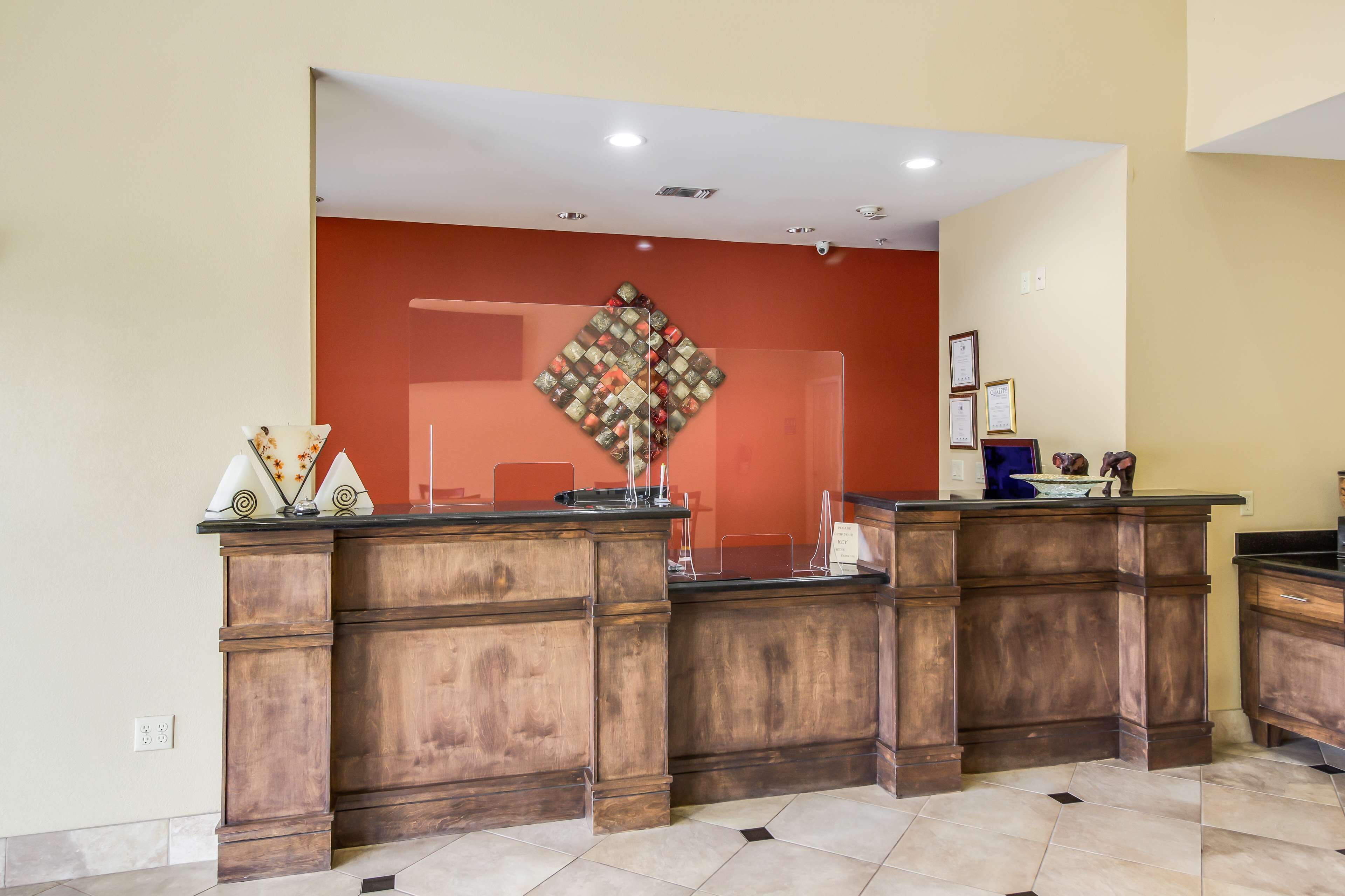 A reception desk with a wooden finish, a red accent wall, and a decorative diamond pattern.