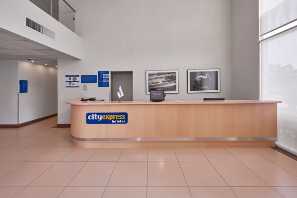 A reception desk with a CityExpress Hotels sign, framed artwork on the wall, and a clear view of the lobby area. - City Express by Marriott Culiacán (Culiacán)