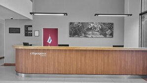 A reception desk with a wooden finish, a flag, and a black and white photograph on the wall.