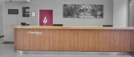 Een receptiebalie met houten afwerking, een vlag en een zwart-wit foto aan de muur.