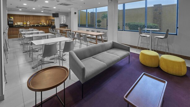 A modern dining area with tables, chairs, a sofa, and ottomans.