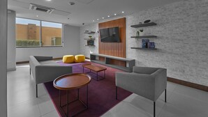 A modern living room with grey sofas, a wooden coffee table, and yellow ottomans.