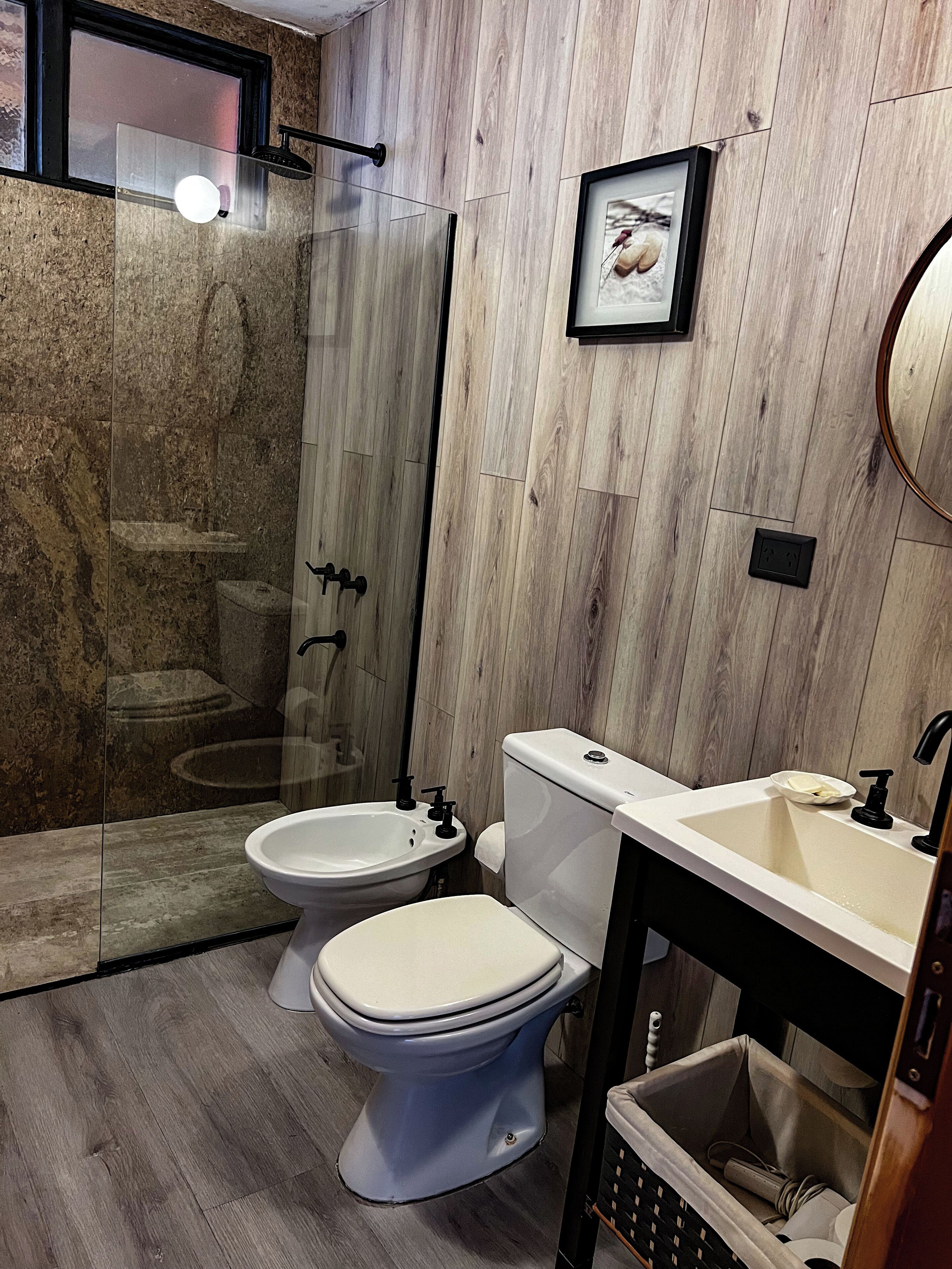 A modern bathroom with a glass-enclosed shower, a toilet, and a sink.